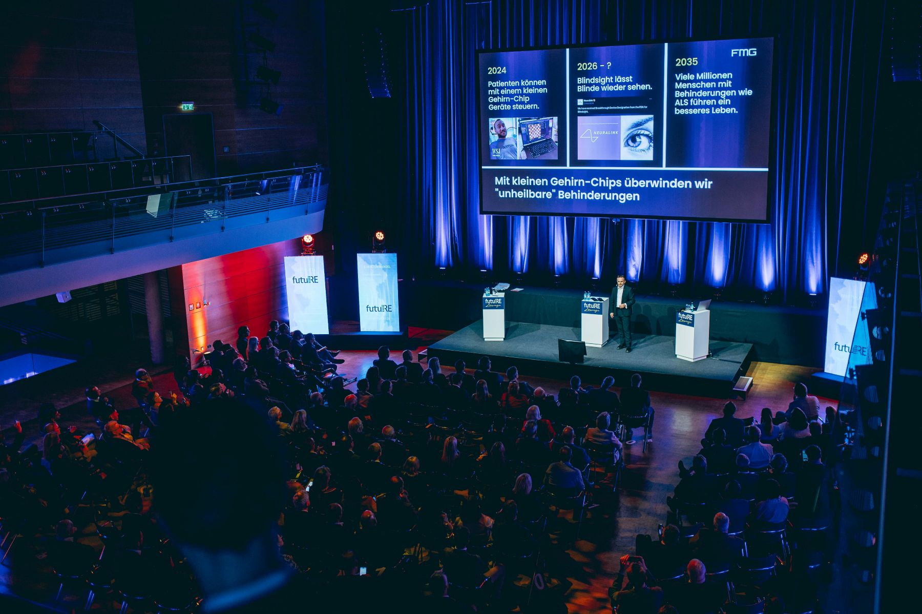 Bild von der Bühne, Blick auf die Leinwand und Keynote-Speaker.
